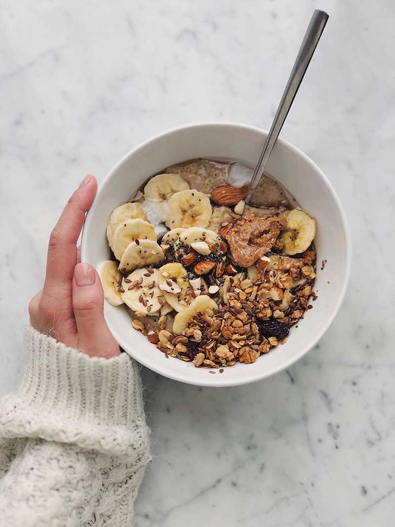 bowl of cereal on marble table with oats, banana and vitamin b12