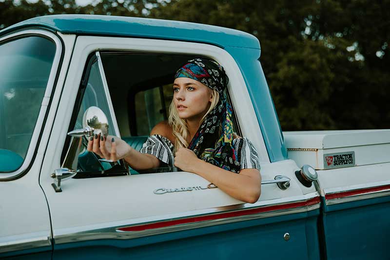 hippy female traveller in classic vintage car.