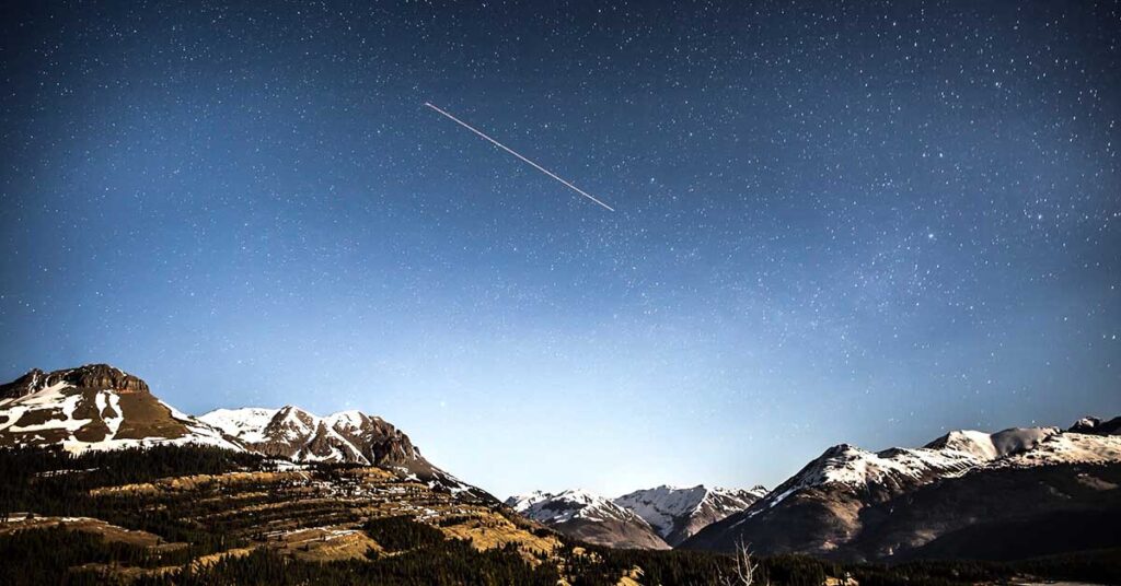 Traveling quotes comet in night sky over mountain range