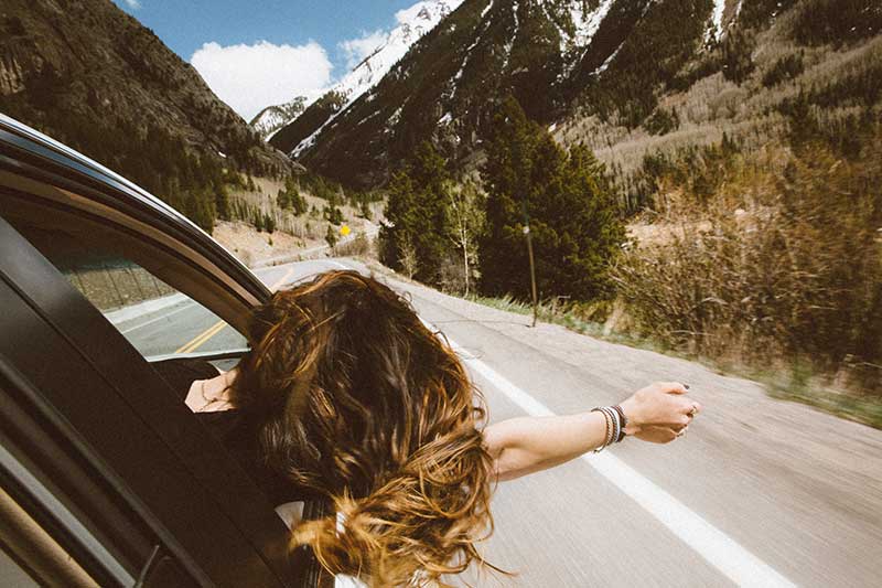 travelling quotes with female explorer in car on road through mountains