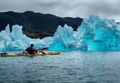 Man in kayak next to iceberg