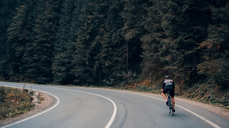 Man cycling near wood.