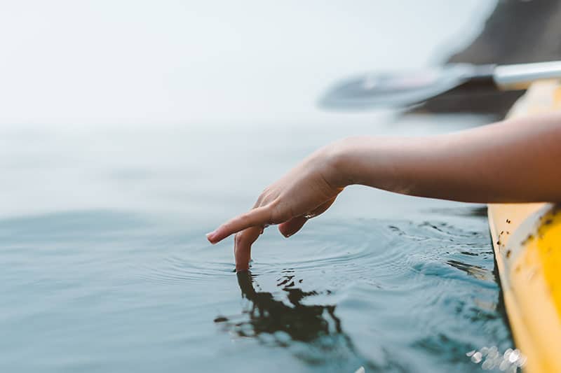 kayaker with hand in the water