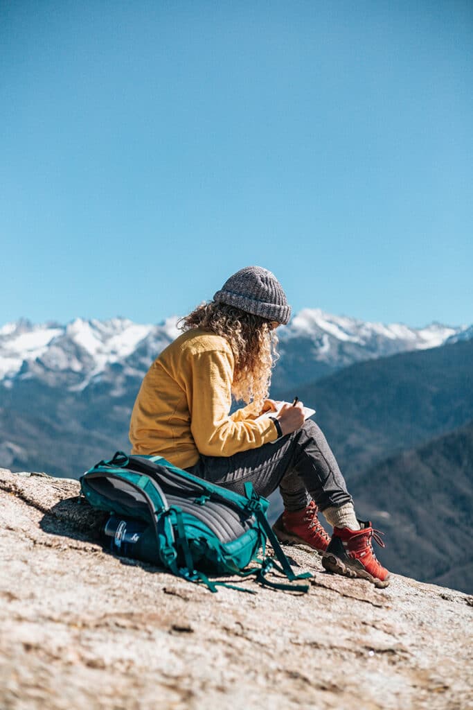 Woman writing while sitting on a rock