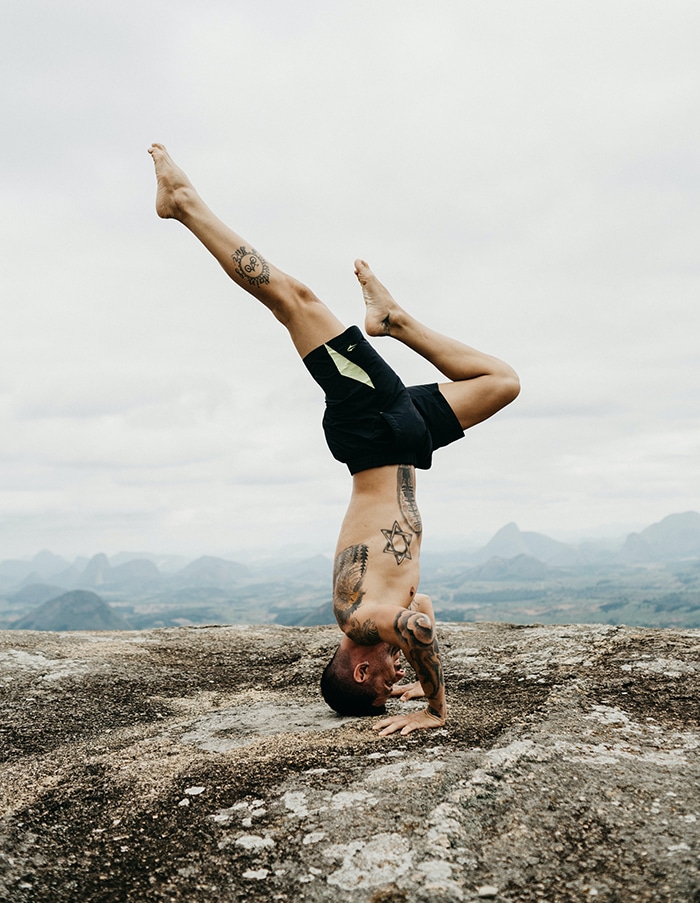 Man performing headstand on rock