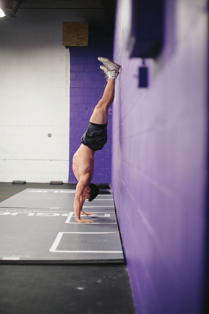 Man performing handstand hold against the wall. 