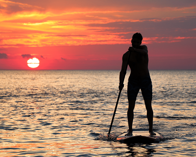 Man on paddleboard at sunset