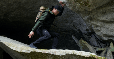 man wearing arcteryx scrambling over rocks