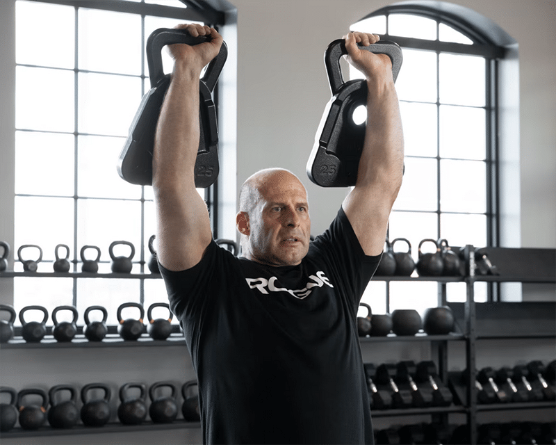 Man lifting cowbells overhead