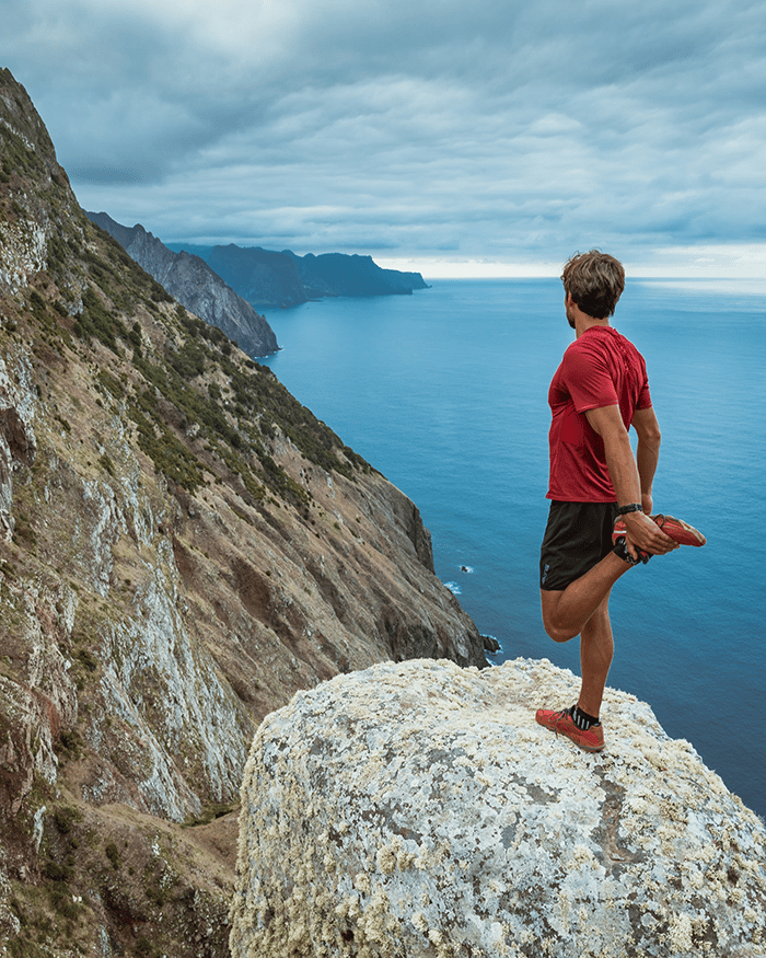 Man stretching on rock in nature.