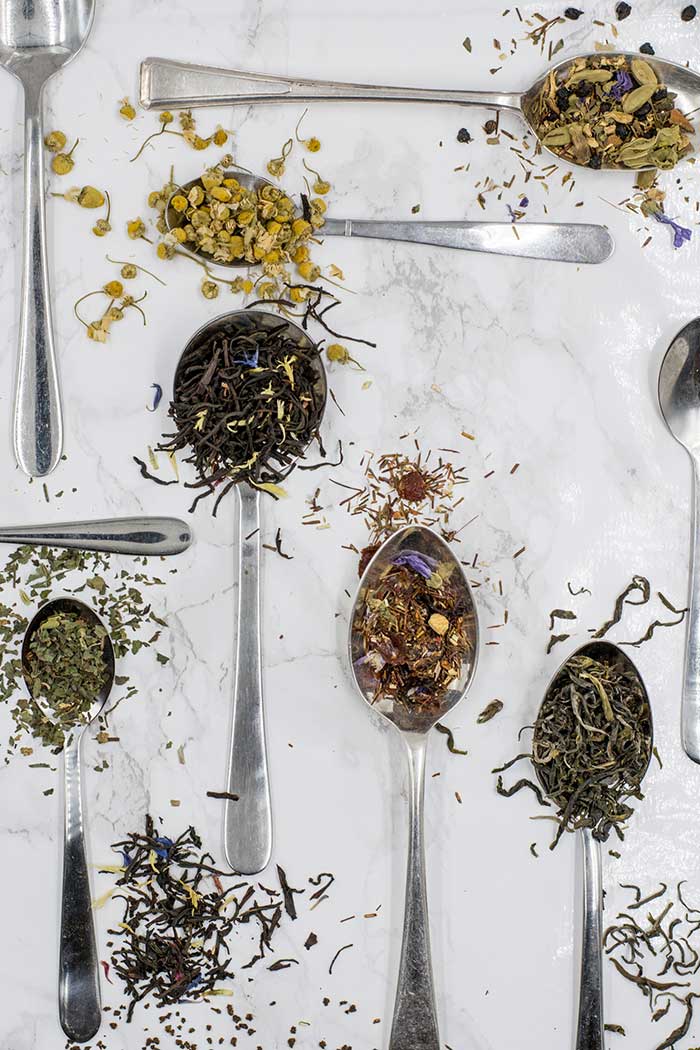 Herbs on spoons showing benefits of pine needle tea.