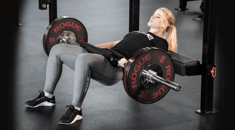 Woman with hip thrust bench and barbell in action