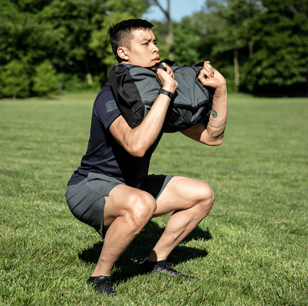 Athlete front squatting with 3 in 1 rogue sandbag.