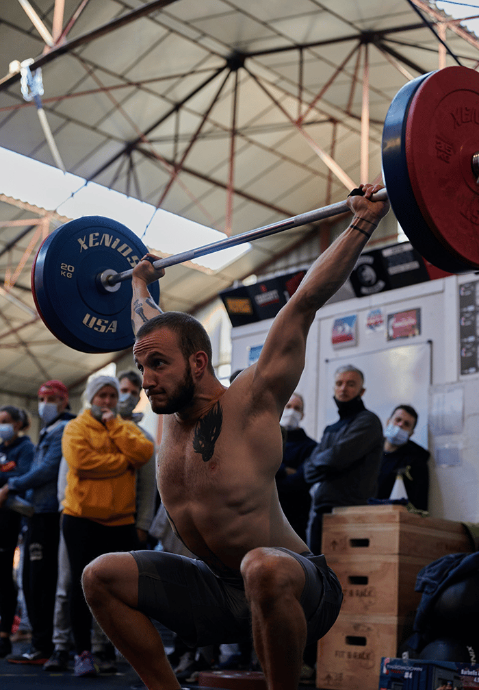 Man snatching barbell in big CrossFit Box