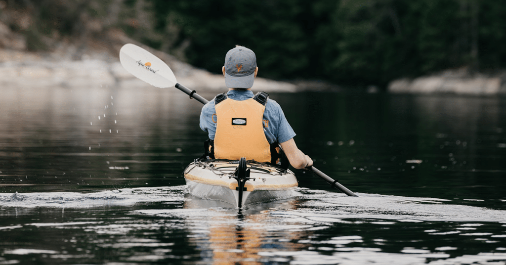 Man kayaking with hat on in lake