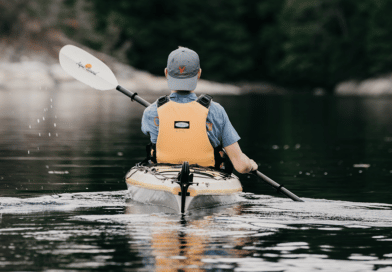 Man kayaking with hat on in lake
