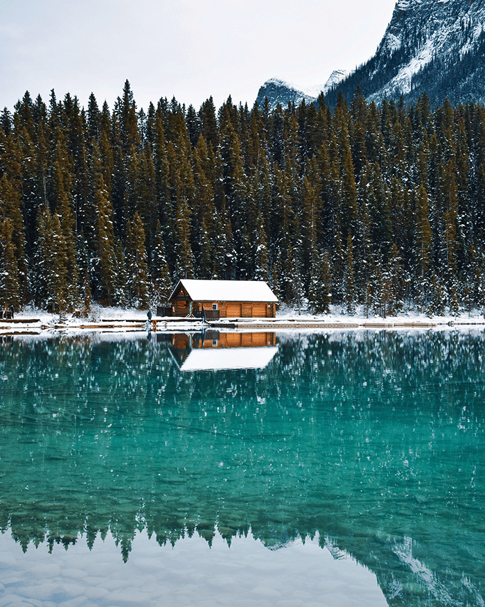House with snow next to lake