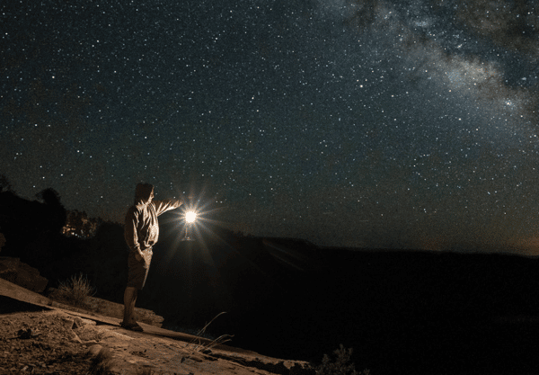 Man with LED camping lantern in night sky