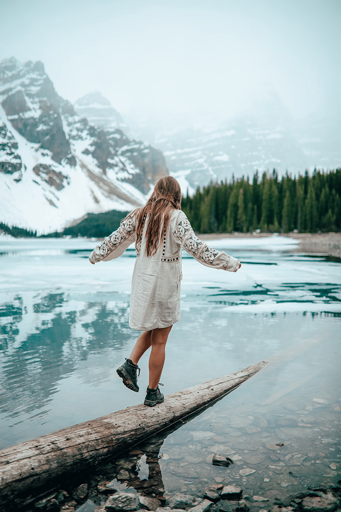 Woman walking on log next to lake