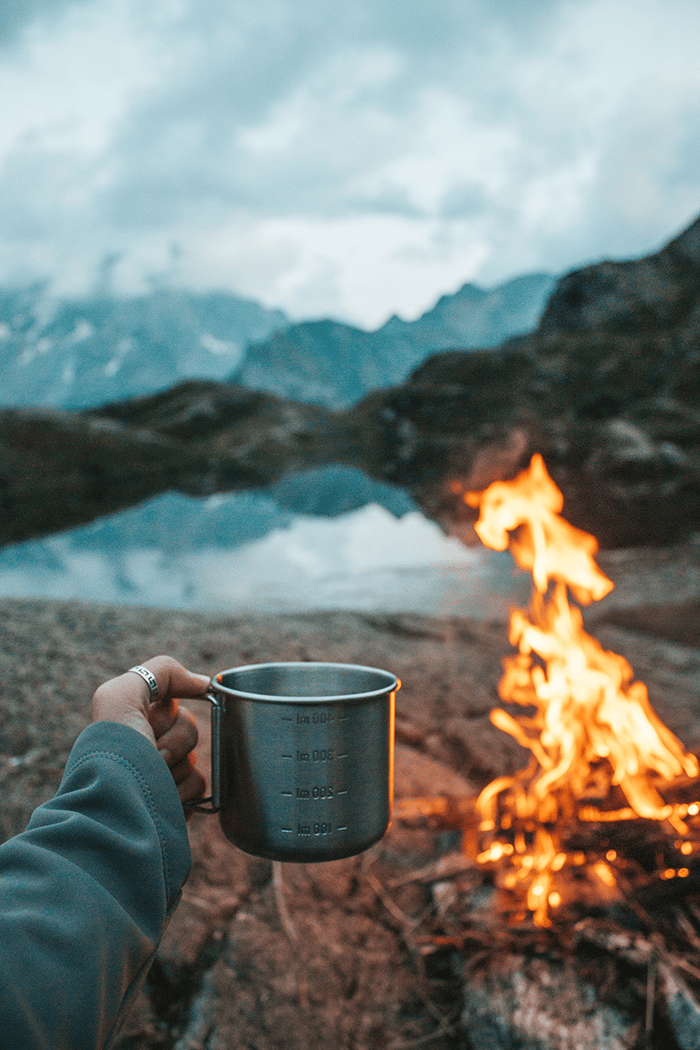 Woman with camping mug and fire