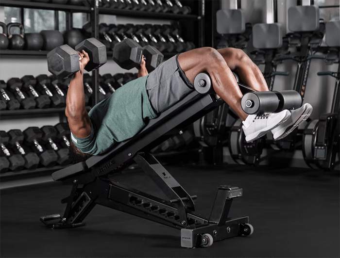 Man on Rogue Manta Ray Adjustable Bench with Dumbbells